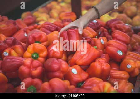 Chicago, IL- August 21, 2021: Woman buying vegetables- fresh red bell peppers at supermarket.  Close up of a woman hands Stock Photo