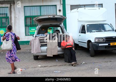 A woman is seen selling clothes out of the trunk of her car in the