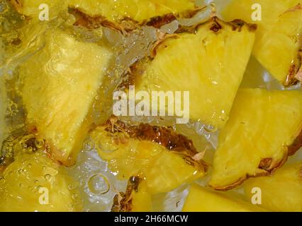 Close-up fresh slices of yellow pineapple on white background. Slices of pineapple in sparkling water on white background, close-up. Horizontal image. Stock Photo