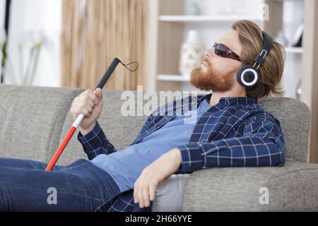 blind man on a sofa using headphones Stock Photo