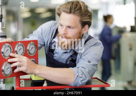 inspector checking pressure gauges on heating boiler system Stock Photo