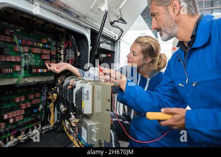 experienced female mechanic checking the engine of a bus Stock Photo