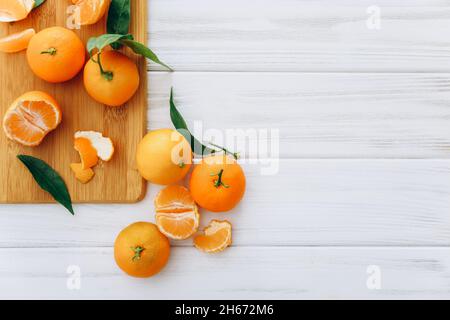 Fresh clementines with leaves on white wooden table. Stock Photo