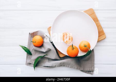 Fresh clementines on plate with grey napkin, top view Stock Photo