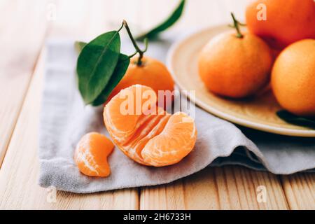 Fresh clementines with leaves and napkin on wooden table. Stock Photo