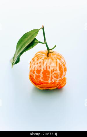Peeled tangerine with leaves on light background Stock Photo