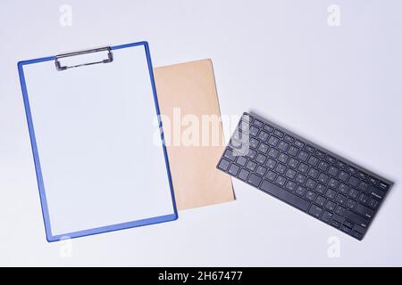 Empty clipboard with white paper, envelope and computer keyboard on white background Stock Photo