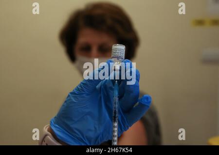A NHS health worker prepares to administer Covid-19 booster jab to a woman at a vaccination centre. Stock Photo