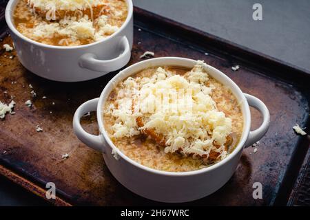 Bowls of French Onion Soup With Toasted Bread and Grated Cheese: Bowls of French onion soup on a sheet pan Stock Photo