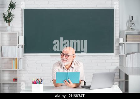 Senior teacher with books and chalkboard. Old smiling professor on ...