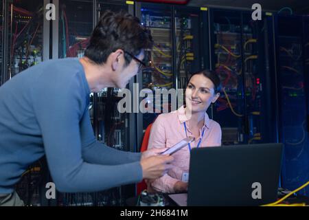 Diverse male and female engineers discussing over a digital tablet in computer server room Stock Photo