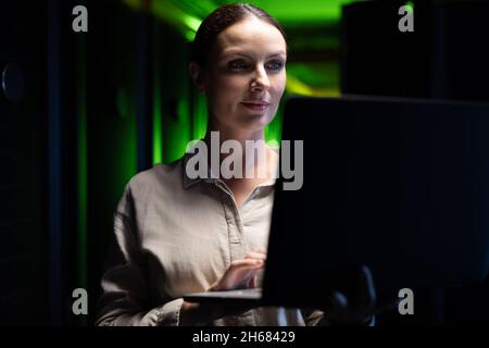 Caucasian female engineer using laptop in computer server room Stock Photo