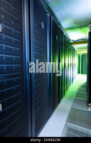 Data center with multiple rows of fully operational server racks Stock Photo