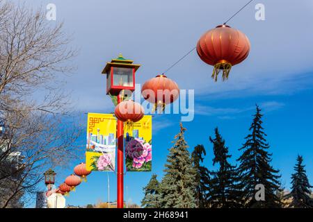 Calgary, Canada - November 13, 2021: Red lanterns hang on Chinese street lamps with colorful banners in downtown Chinatown in Calgary. Stock Photo