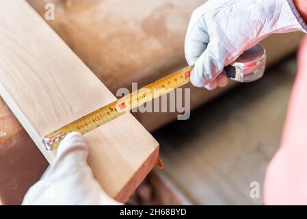 Person measuring a wooden plank with a meter Stock Photo