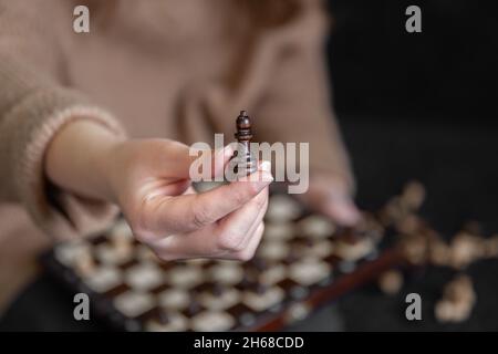 Close-up of a chess piece in female hands, blurred background. Stock Photo
