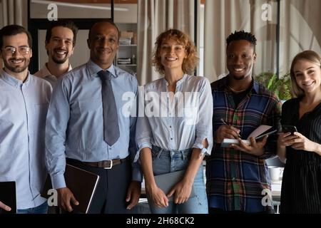 Smiling young mixed race business people posing in modern office. Stock Photo