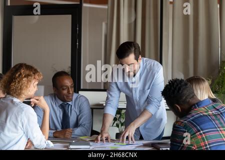Concentrated young male leader analyzing reports with colleagues. Stock Photo