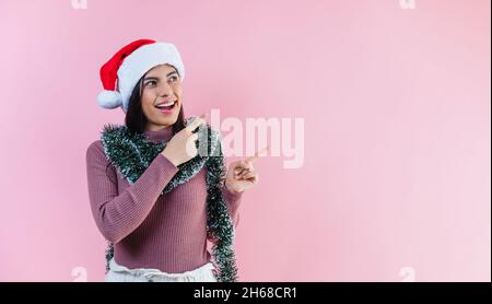 Portrait of young latin woman with copy space in a christmas concept on pink background Stock Photo