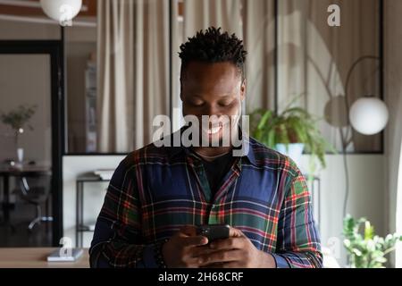 Smiling young african man using cellphone applications. Stock Photo