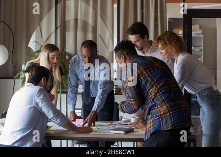 Concentrated young mixed race teammates analyzing paper reports. Stock Photo