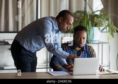 Skilled african ethnicity leader coaching multiracial colleague. Stock Photo