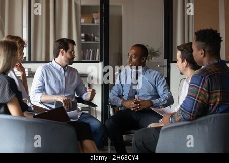 Concentrated young mixed race business people discussing project ideas. Stock Photo