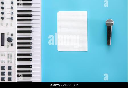 Musical keys, microphone and blank paper on a blue background. Stock Photo