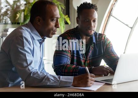 Focused two diverse employees working on online project. Stock Photo