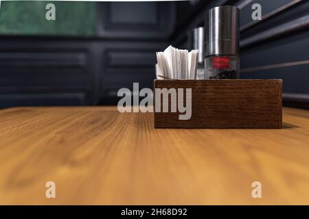 Wooden box with spices and napkins on a table in a cafe. Stock Photo