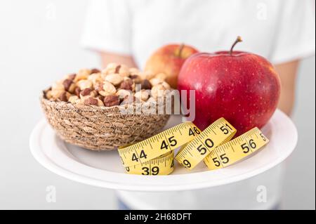 Plate with apples, nuts and measuring tape, diet and healthy food concept. Stock Photo