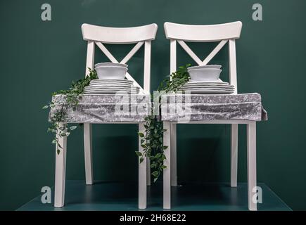 Kitchen composition with a set of dishes on white chairs. Stock Photo