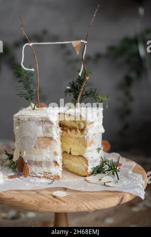 Rustic birthday cake, side cut, white cakes with butter cream, wall background, sponge cake. Decorated wedding cake. Homemade cakes on a table Stock Photo