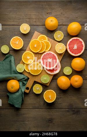 Fresh juicy vitamin oranges, grapefruits, limes on wooden board. Citrus halved. Variation of sour mixed sliced mandarin. Colorful exotic tropical vege Stock Photo