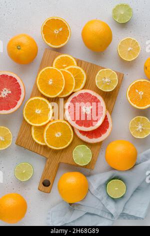 Colorful juicy summer oranges, grapefruits, limes, lemons on wooden board. Sliced fruits full of vitamic C. Assorted composition of ripe multifruits. Stock Photo