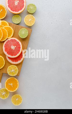 Colorful juicy summer oranges, grapefruits, limes, lemons on wooden board. Sliced fruits full of vitamic C. Assorted composition of ripe multifruits. Stock Photo