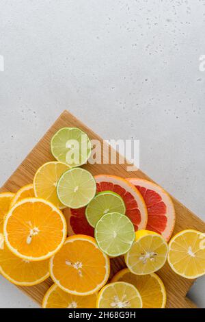Exotic citrus composition on chopping board. Many juicy halved lemons, limes, grapefruits. Vitamin c healthy varation. Summer mood. Vivid tropical rip Stock Photo