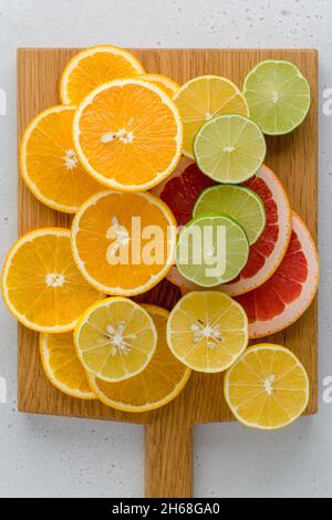 Exotic citrus composition on chopping board. Many juicy halved lemons, limes, grapefruits. Vitamin c healthy varation. Summer mood. Vivid tropical rip Stock Photo