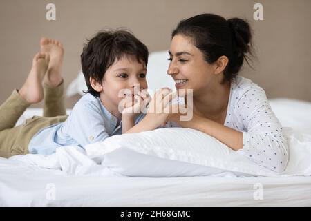 Happy Indian little boy and cheerful mom resting in bed Stock Photo