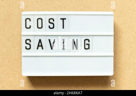 Lightbox with word cost saving on wood background Stock Photo