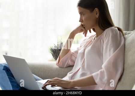 Pensive young woman thinking on problem solution, working on computer. Stock Photo