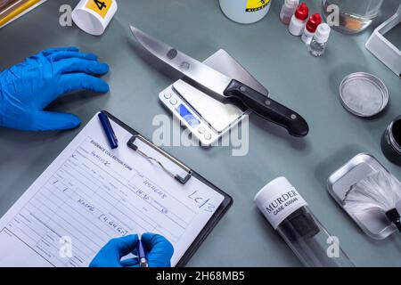 crime police weigh knife involved in murder, record data in crime lab, concept image Stock Photo
