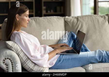 Relaxed happy young woman using computer at home. Stock Photo