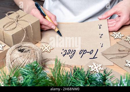 Writing a to-do list, Wish list for new year christmas - a hand writing with a pen on empty recycled paper on a table with Christmas decorations. Goal Stock Photo