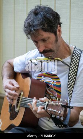 Waikiki, Honolulu, Hawaii - Oct 31, 2021-Man plays harmonica and acoustic guitar. Stock Photo