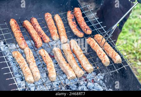 Grilled sausages are cooked on a charcoal grill outdoors. Grilling sausages on barbecue grill. Street food Stock Photo