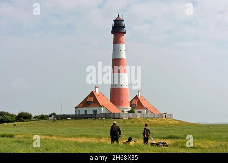 Hikers at the lighthouse Westerheversand,Westerhever, Eiderstedt peninsula, Schleswig-Holstein Wadden Sea National Park, Schleswig-Holstein, Germany