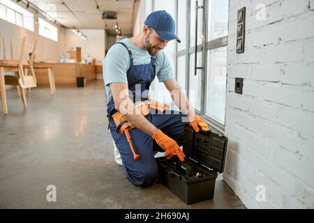 Male electrician using tool box to repair electrical socket Stock Photo