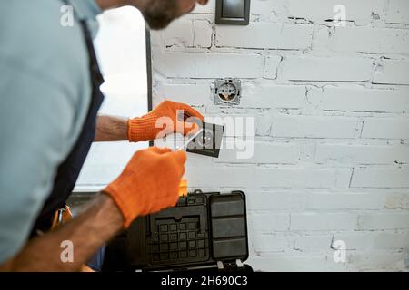 Man hands fixing electrical wall socket with screwdriver Stock Photo