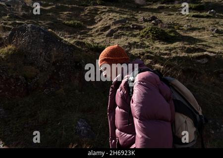 A mountaineer, senior adult man, in his 70s, wearing a feather coat and sunglasses, enjoys a hike up the mountain, Pyrenees, Spain Stock Photo